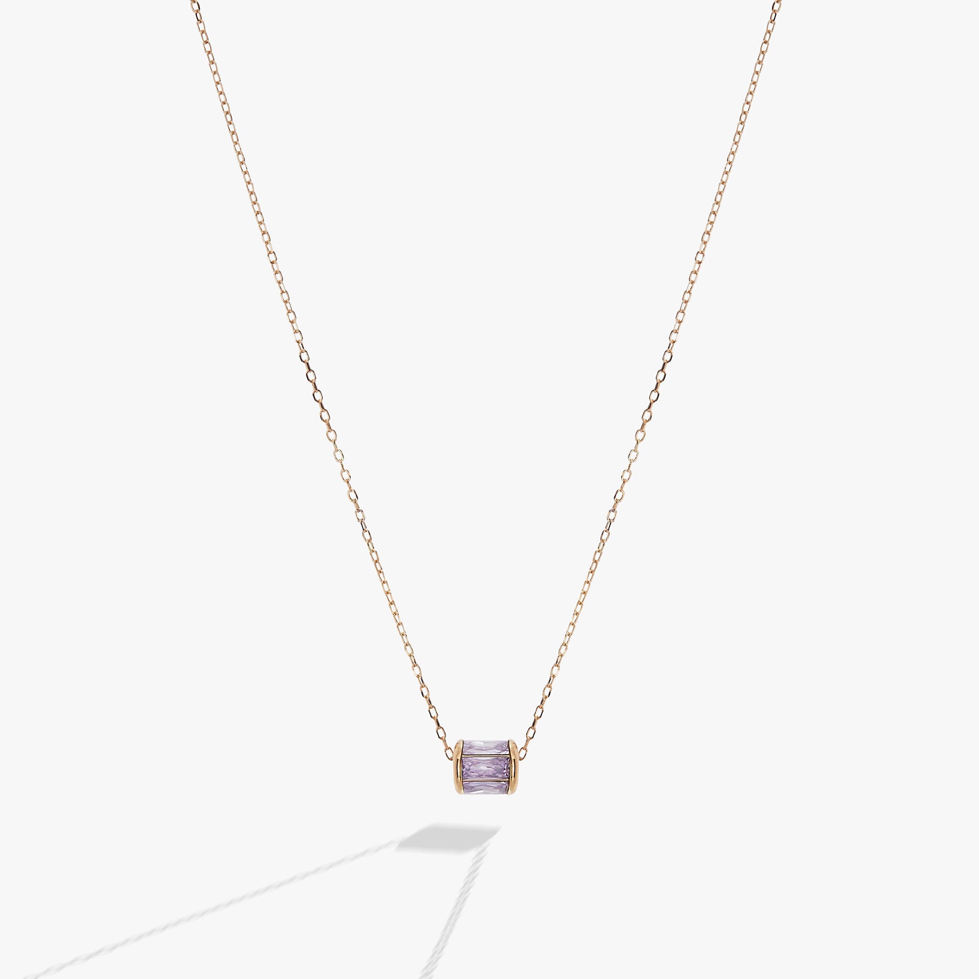 Minimalist gold chain necklace featuring a small, baguette-cut light purple amethyst crystal pendant.