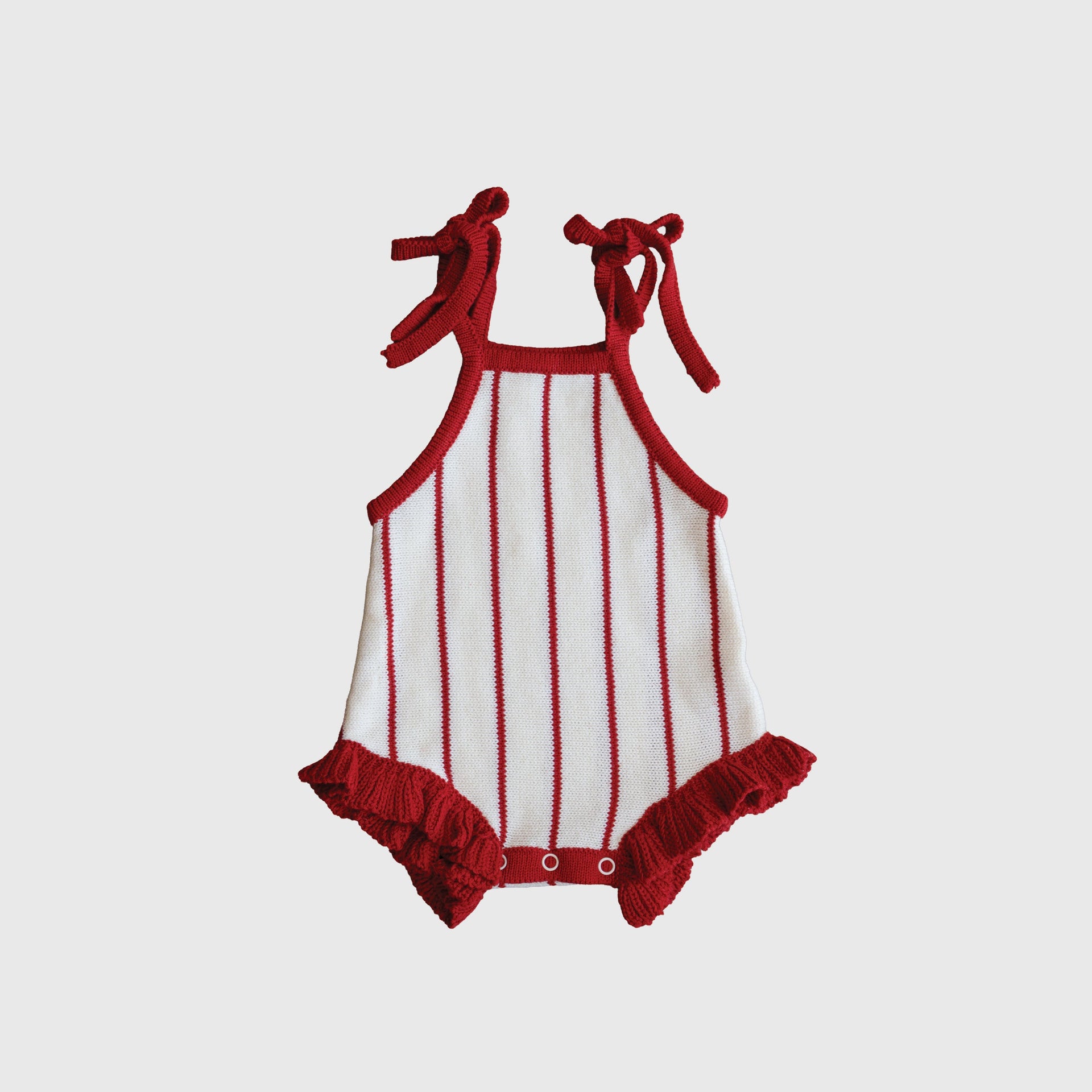 Baby wearing a red and white pinstripe knit romper with ruffles and snap closures