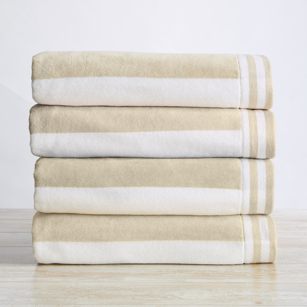 A stack of folded 100% cotton cabana-style beach towels with white and beige stripes and detailed border texture.