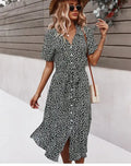 A woman wearing a floral print midi dress with a V-neck and tie waist, standing outdoors.