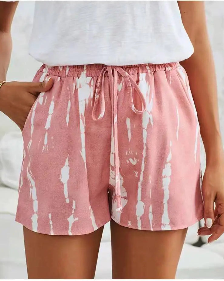 Pink shorts with white pattern worn by a person on a blurred background
