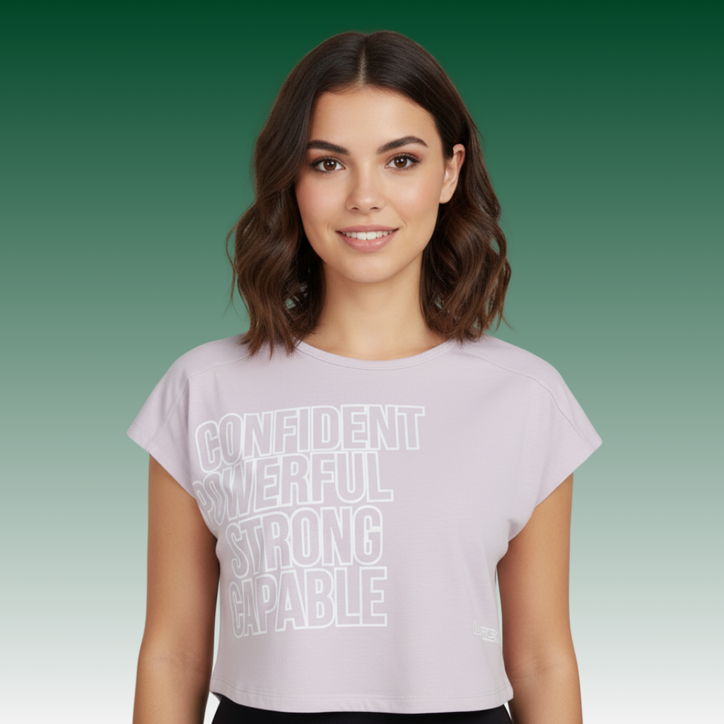 Women wearing a lavender-pink cropped graphic tee with the words Confident, Powerful, Strong, Capable in white lettering.