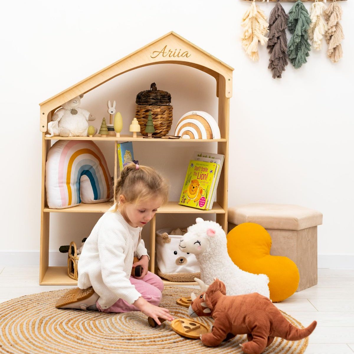 Three-storey wooden dollhouse bookshelf in a minimalist Scandi style.