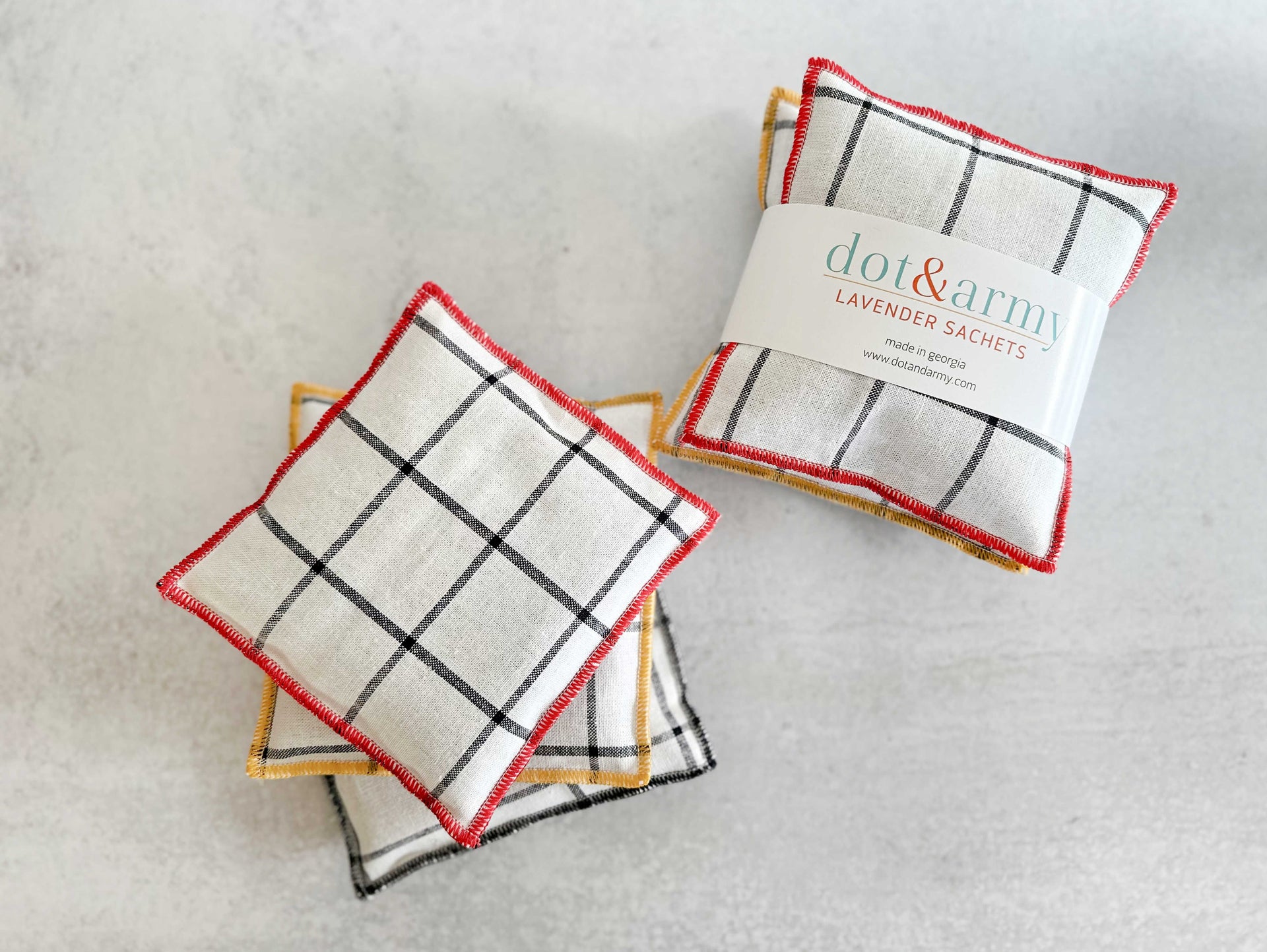 A set of two linen lavender sachets featuring a windowpane pattern and colorful edge stitching.