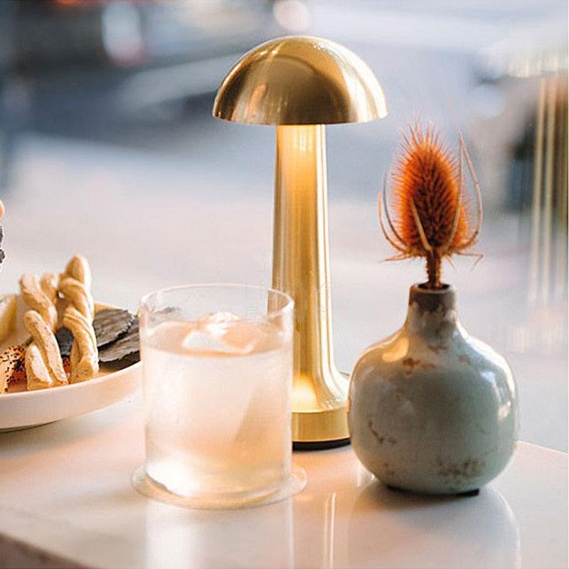 Modern metallic portable table lamp with touch sensor on a nightstand.