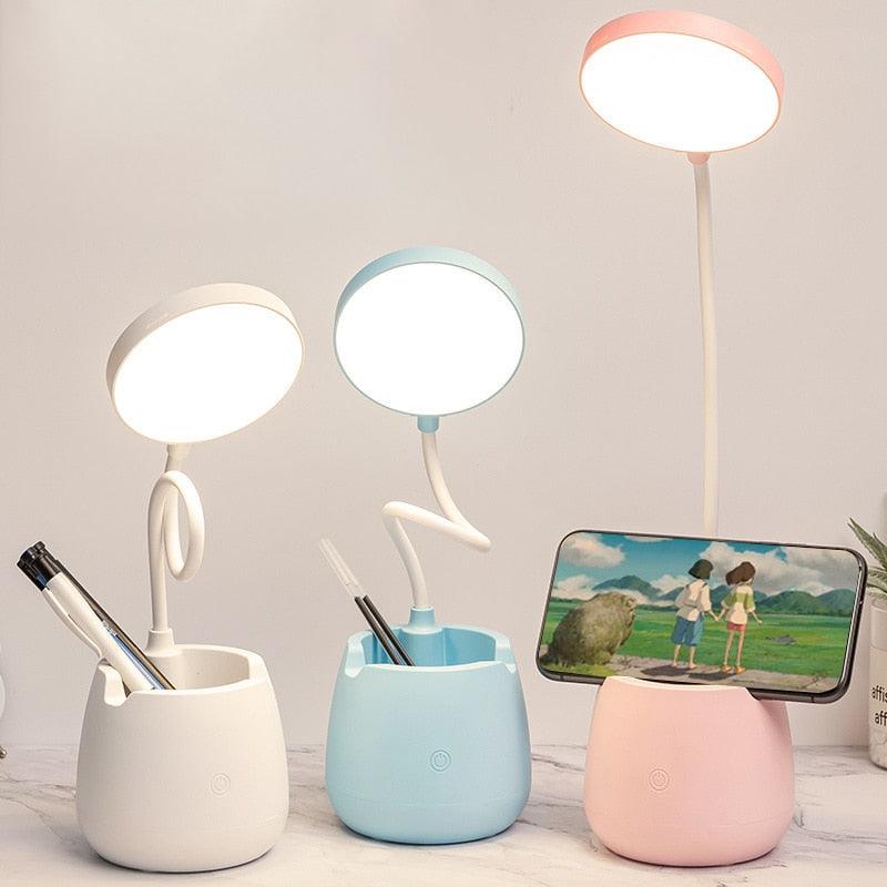 Dimmable LED desk lamp with a built-in pen holder on a workspace.