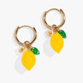 Gold huggie hoop earrings featuring a yellow lemon motif with green leaves and white blossoms.