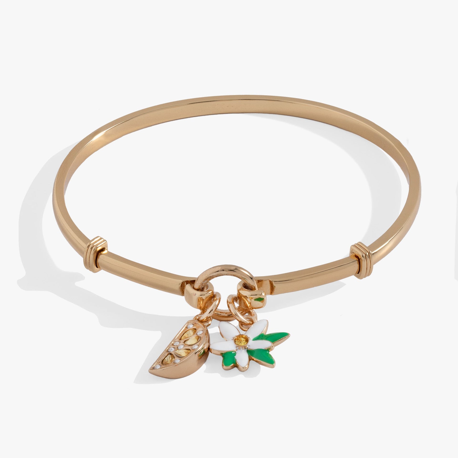 Gold tension bangle featuring a yellow crystal-encrusted lemon wedge charm and a white flower charm.