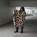 Modern earth-toned leopard print knit throw blanket draped over a neutral sofa in a cozy living room