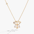 Gold-plated Libra zodiac necklace featuring a scale charm with clear crystal triangle accents