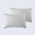 Set of two light grey cooling pillowcases on a white bed sheet.