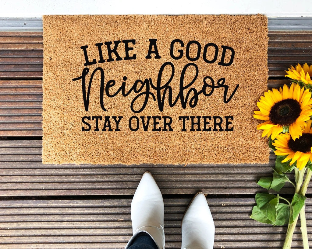 Funny tan and black doormat with the text Like A Good Neighbor Stay Over There