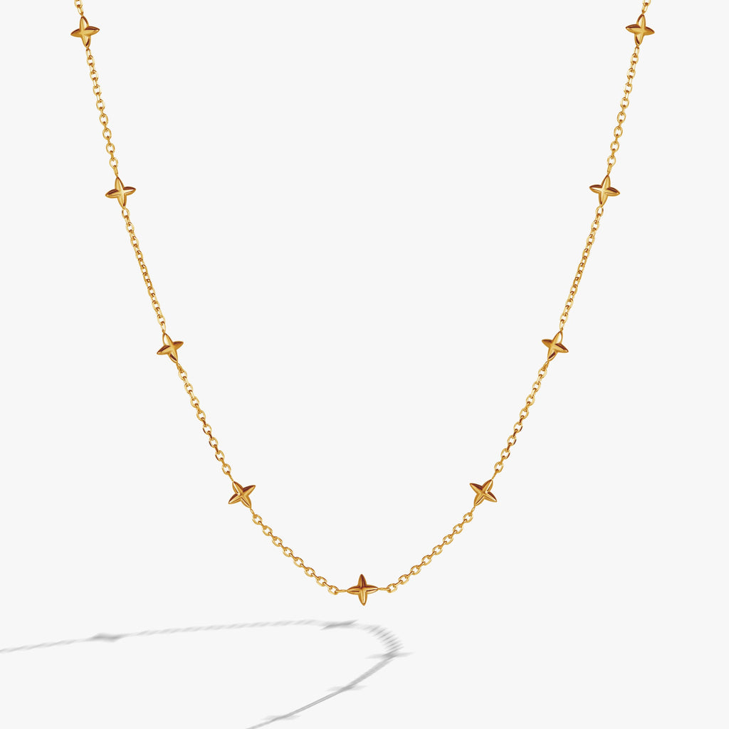 Close-up of a minimalist gold cable chain necklace featuring beveled four-point star stations.