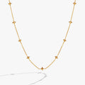 Close-up of a minimalist gold cable chain necklace featuring beveled four-point star stations.