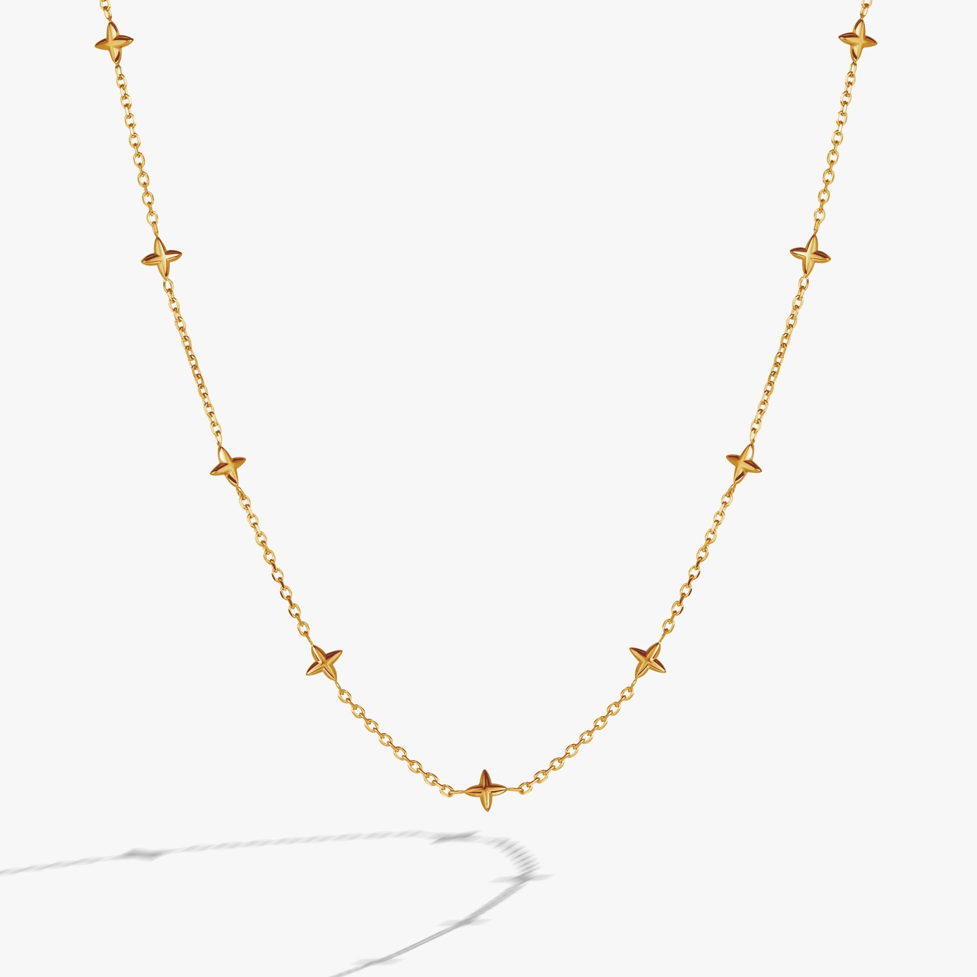 Close-up of a minimalist gold cable chain necklace featuring beveled four-point star stations.