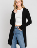 A long black ribbed duster cardigan worn as a stylish layering piece over casual clothing.