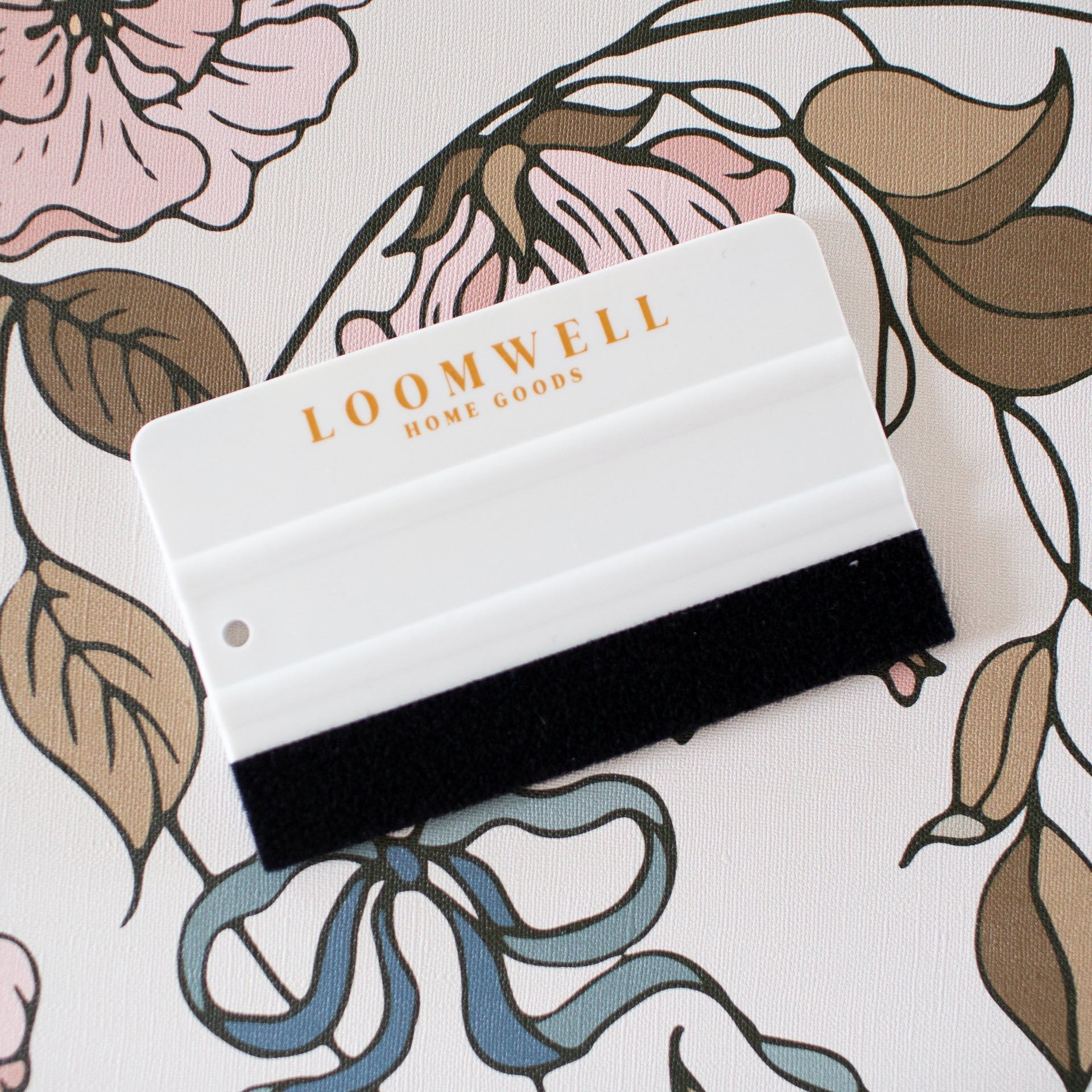 Monochrome 4-inch wallpaper squeegee with white plastic handle and black felt edge for scratch-free application.