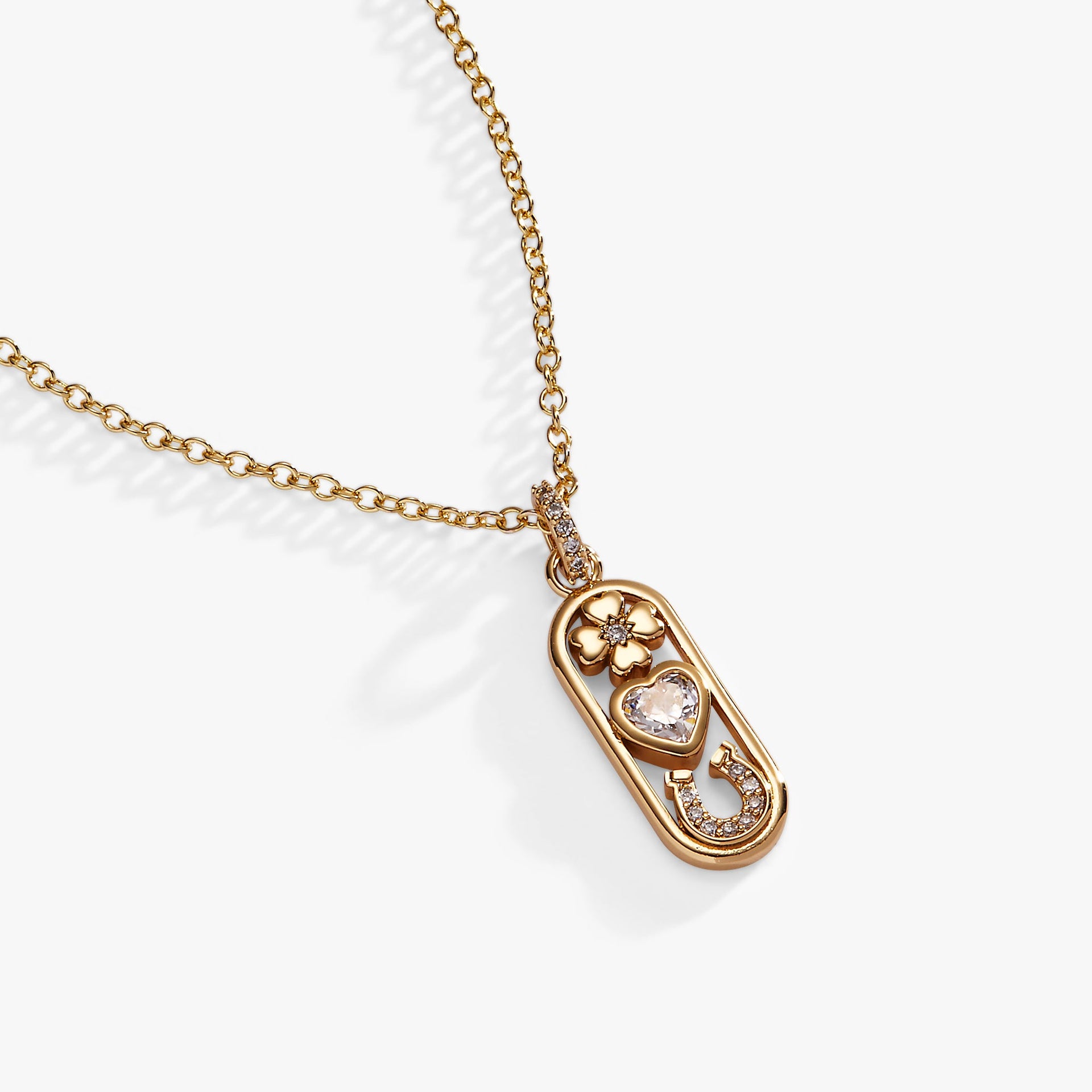 Close-up of a gold-tone Love and Luck pendant necklace featuring a four-leaf clover, heart crystal, and horseshoe charm.
