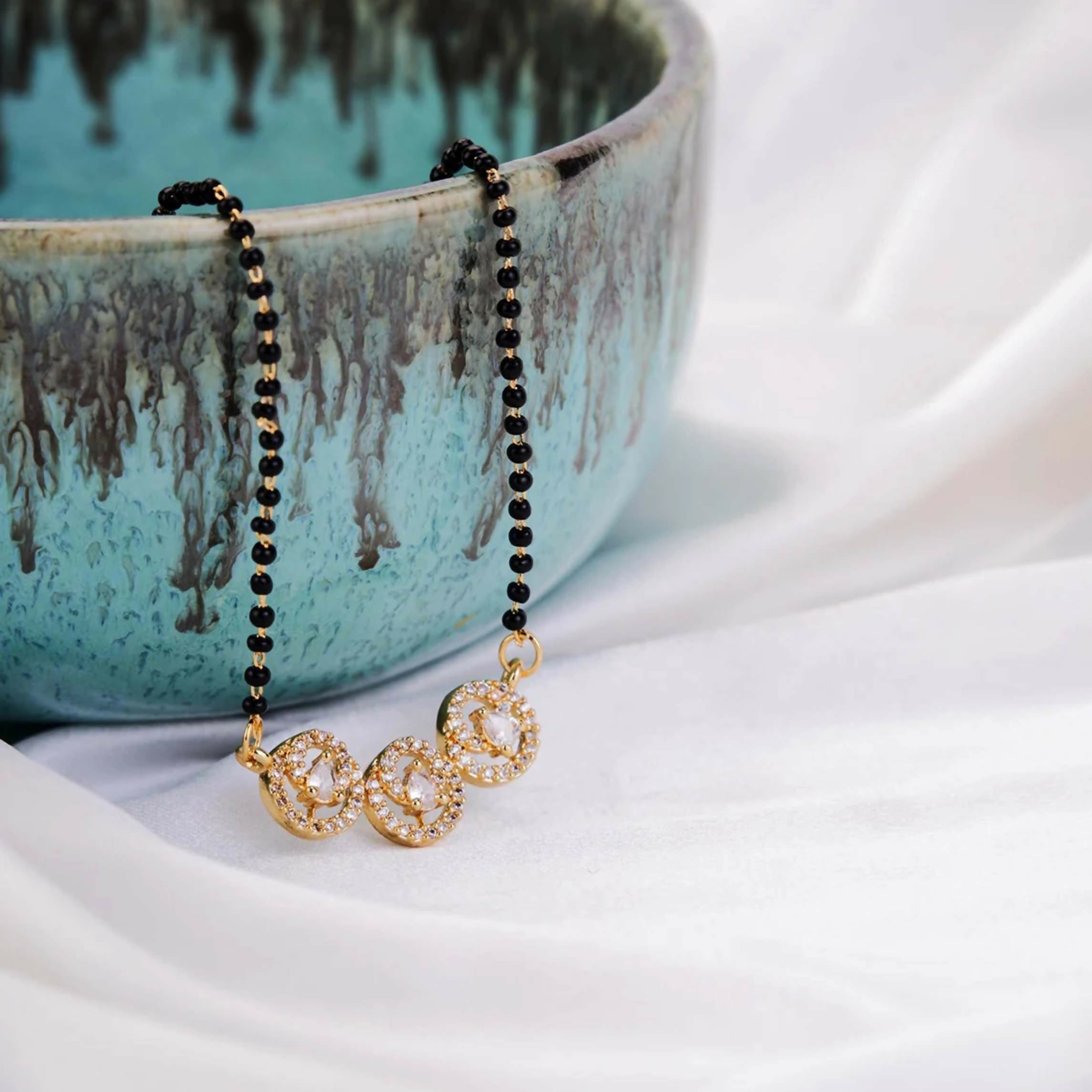Close up of a Gold Tone AD Mangalsutra necklace featuring intricate traditional design on a white background.