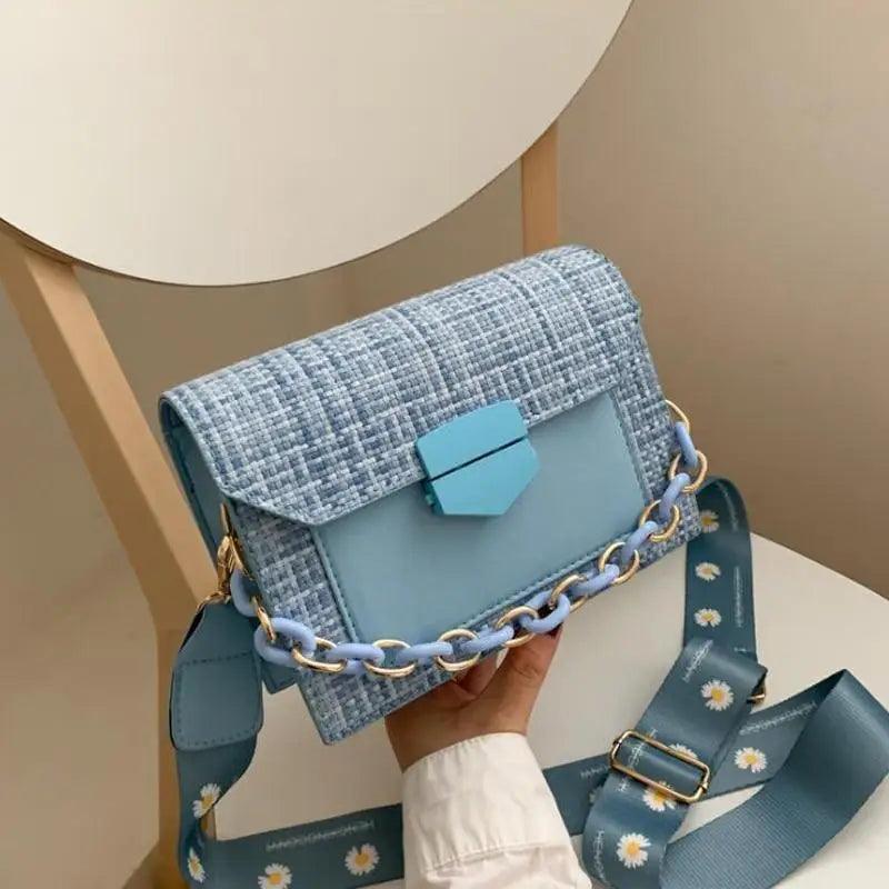 Luxury wide-strap crossbody bag with chain detailing and elegant designer aesthetic
