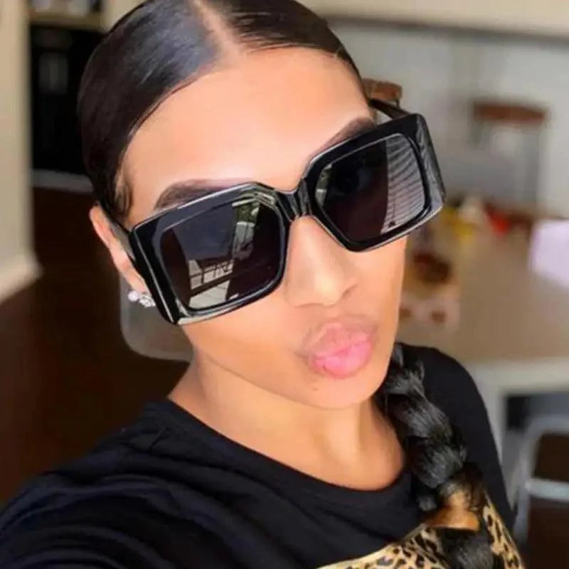 Woman wearing modern oversized square sunglasses in black, showcasing a streetwear fashion aesthetic.