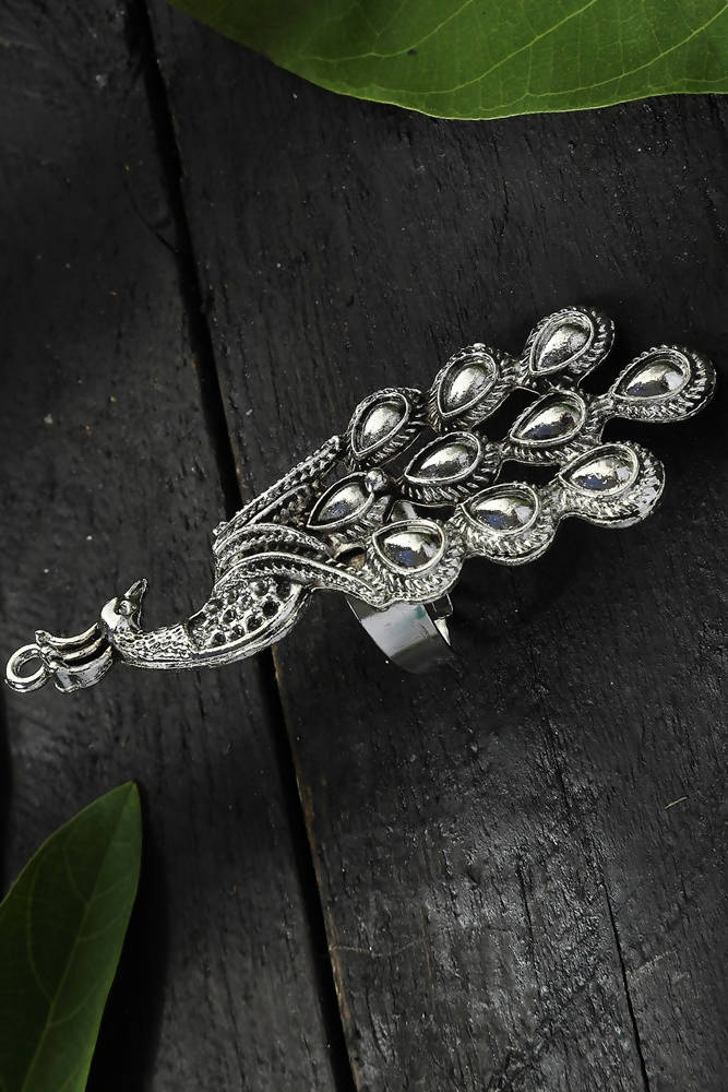 Close up of an oversized oxidised silver peacock statement ring worn by a woman