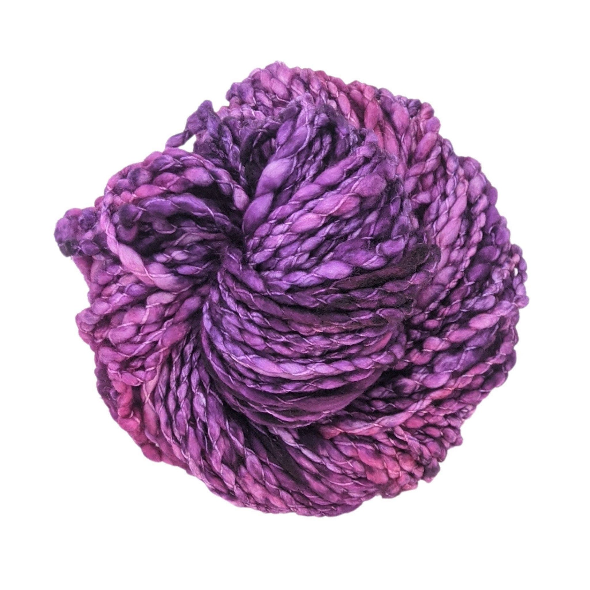 Skein of Malabrigo Caracol yarn in deep purple, magenta, and teal variegated jewel tones