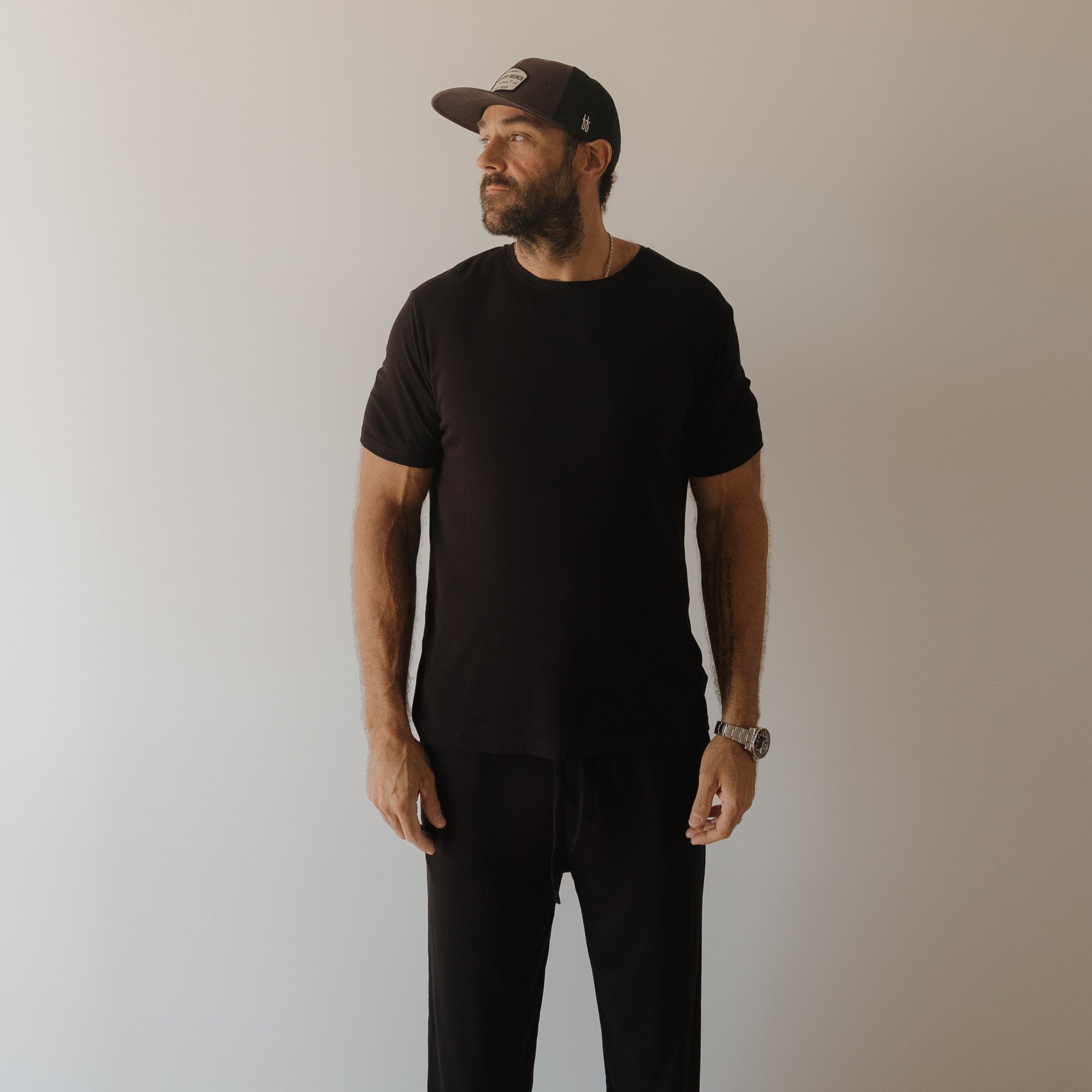 Men wearing a black ribbed bamboo short sleeve pajama set with full-length pants.