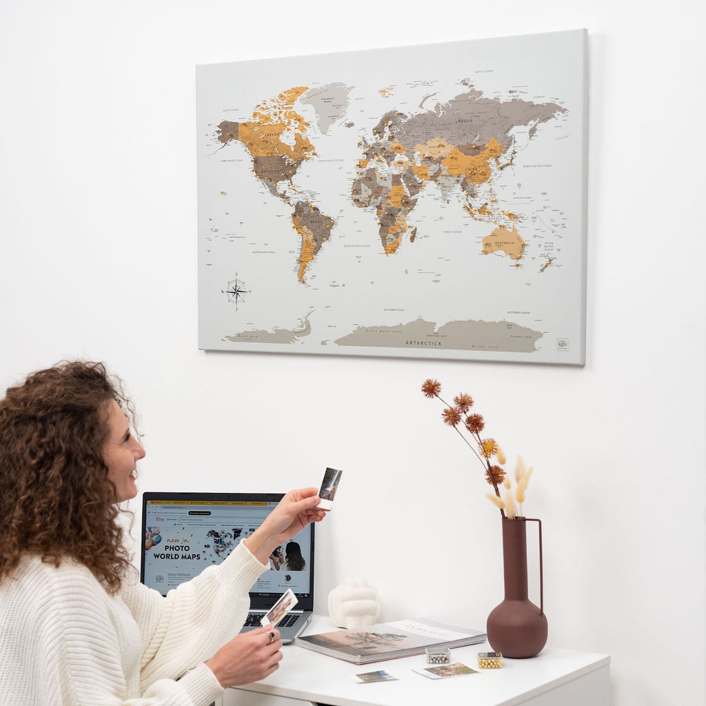 Minimalist world map canvas featuring a grey, gold, and brown desert-inspired palette on a modern wall.