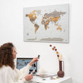 Minimalist world map canvas featuring a grey, gold, and brown desert-inspired palette on a modern wall.