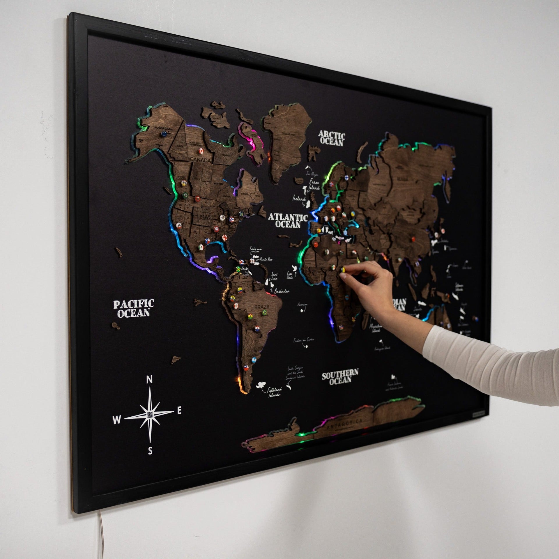 Large Dark Walnut LED world map on a black background mounted in a modern living room