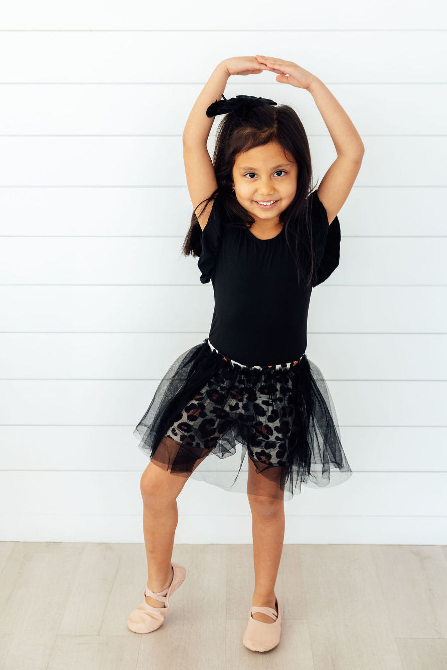 Young girl modeling leopard print tutu shorts with a black tulle overlay while dancing