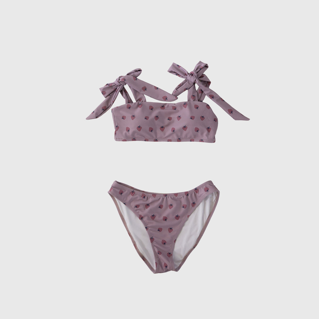 Woman wearing a Matilda mauve two-piece swimsuit with pink strawberry print and tie-shoulder straps.