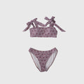 Woman wearing a Matilda mauve two-piece swimsuit with pink strawberry print and tie-shoulder straps.