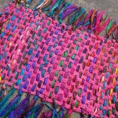 Close up of a handcrafted crochet meditation mat featuring textures from Lux Adventure yarn and Bahamas ribbon.