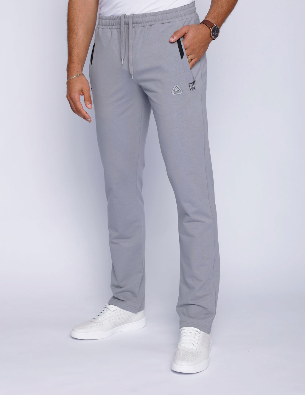 Model wearing grey straight-fit athletic sweatpants with side zippered pockets and a drawstring waistband.