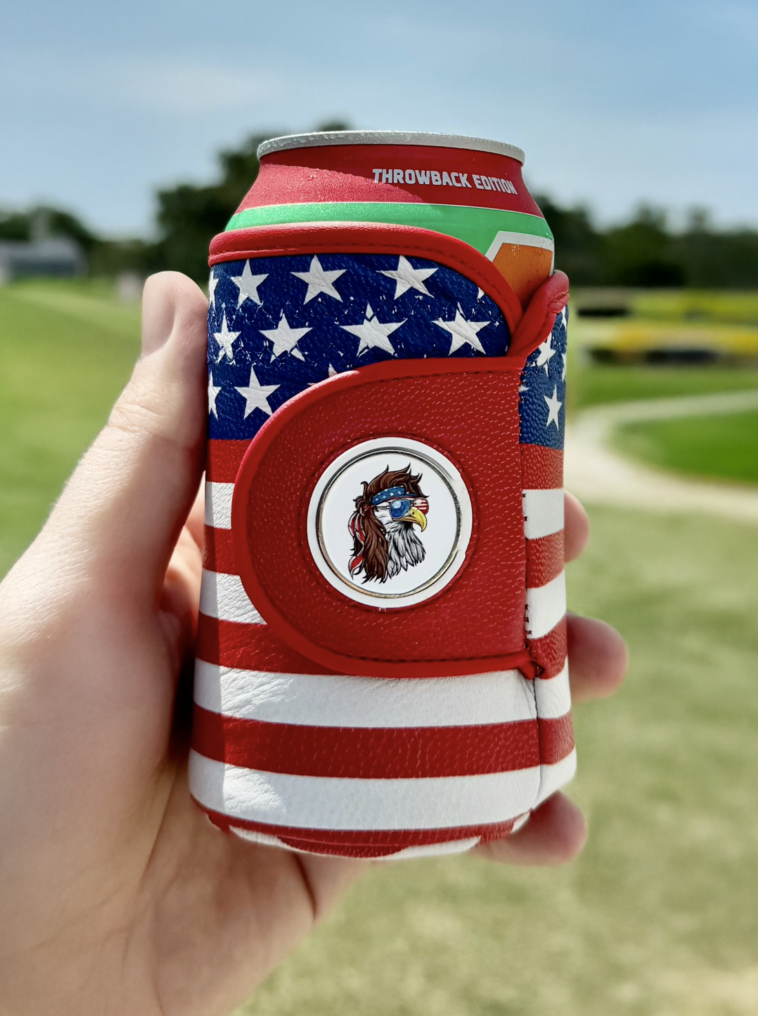 American flag print leather drink sleeve with a magnetic ball marker showing a bald eagle or statue of liberty on a golf course background.