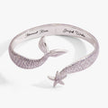 Silver-tone cuff bracelet with iridescent lavender enamel and a delicate starfish charm.