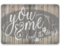 Rustic metal sign featuring the text You Me & The Dogs with paw prints on a wood plank background