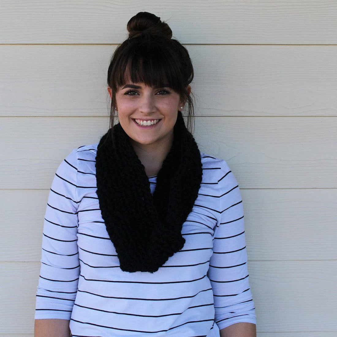 A stylish, solid black crocheted scarf with thick and thin texture draped elegantly.