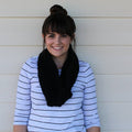 A stylish, solid black crocheted scarf with thick and thin texture draped elegantly.