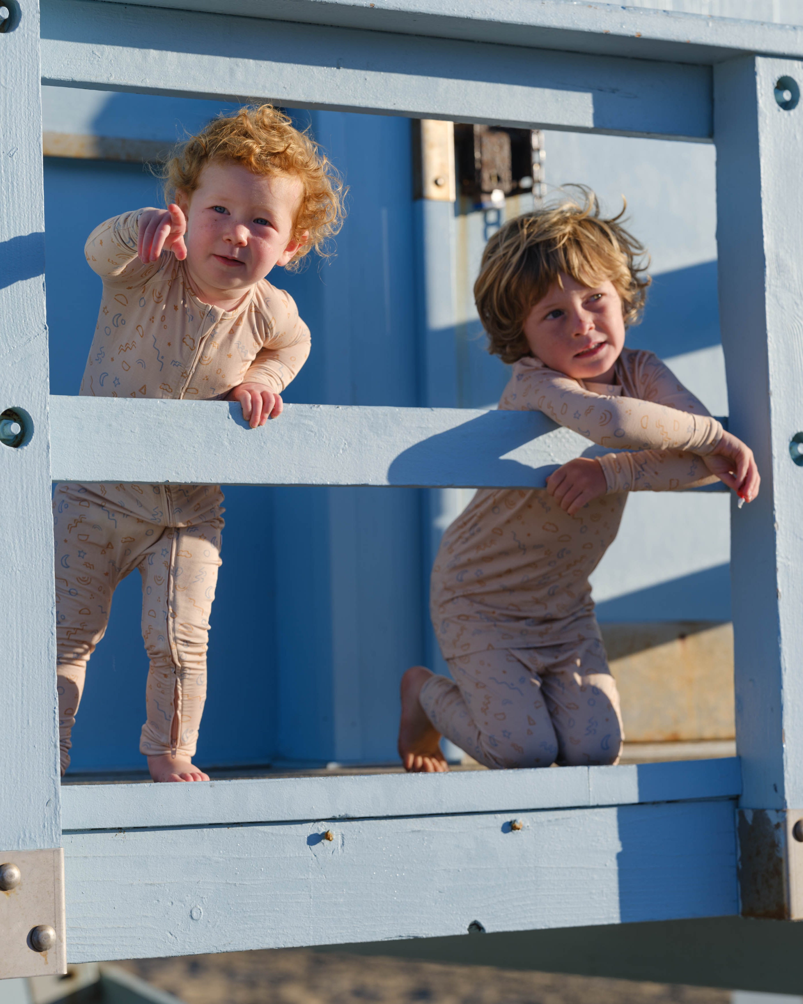 Two children playing on a playground structure with a mirror.
