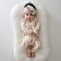 Baby wearing a one-piece bamboo zip pajama with a brown milk carton print pattern