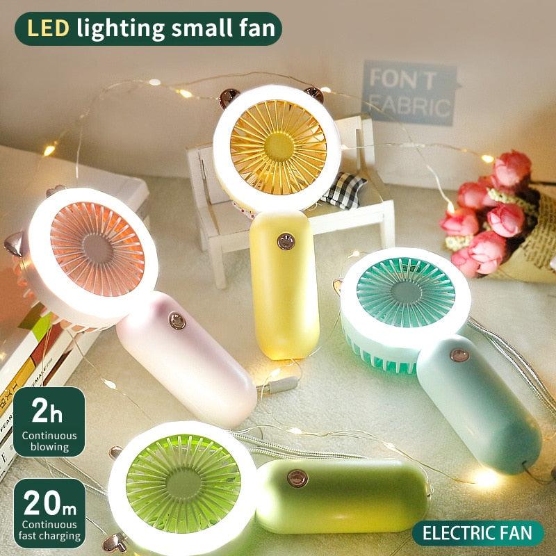 A pastel pink portable mini USB fan with an integrated LED night light, sitting on a clean desk surface.