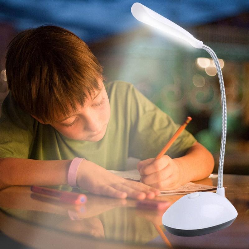 Foldable white portable LED desk lamp on a workstation for student reading.