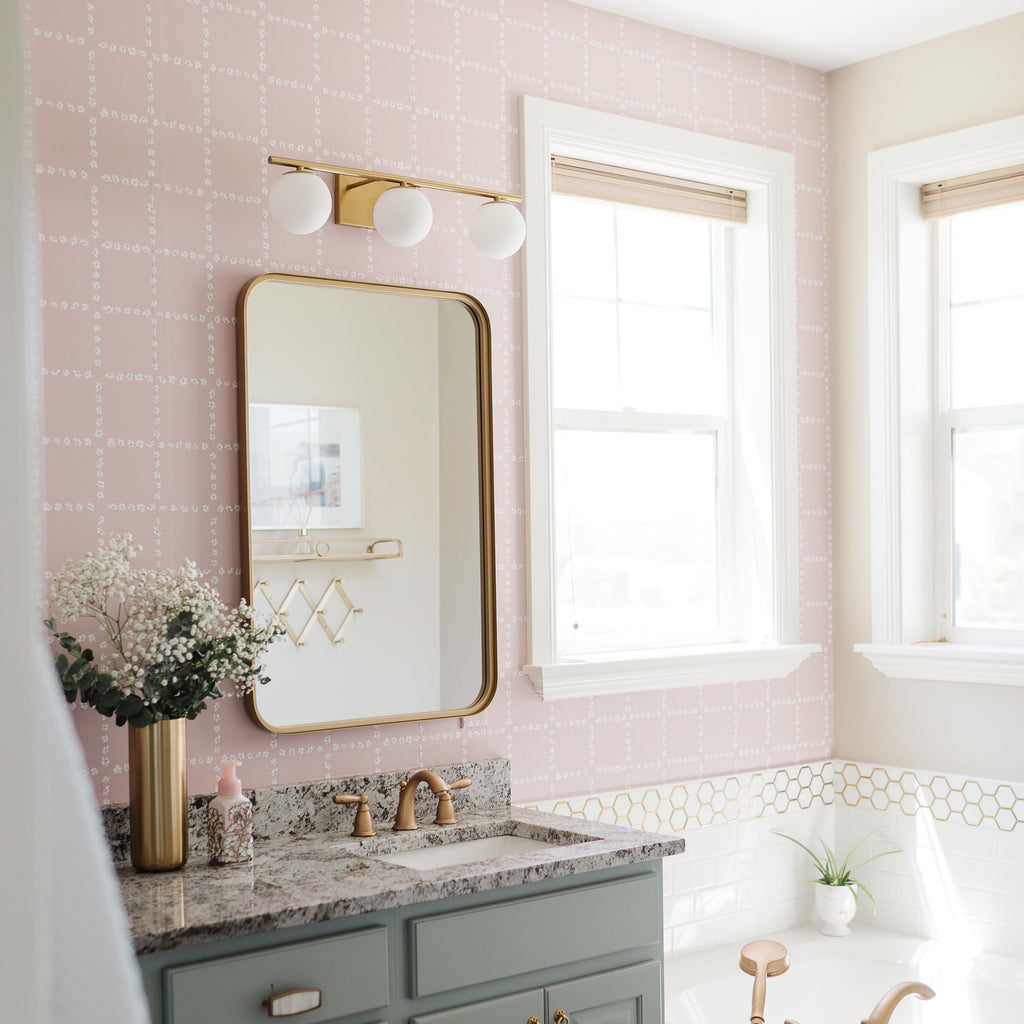 Close up of Shae geometric wallpaper with soft blush pink dashed grid lines on a white background in a modern bedroom setting.