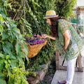 A woman wearing a bohemian, oversized, variegated green, blue, and yellow open knit crochet poncho outdoors.