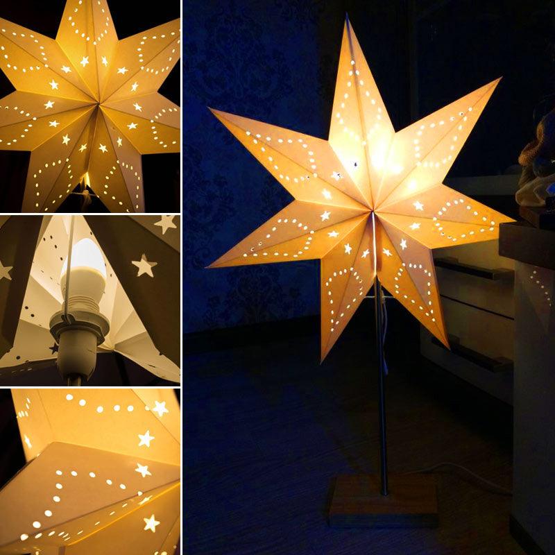 Decorative paper star table lamp with a wood base on a minimalist side table