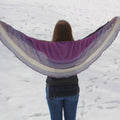 Moonbeam Crescent Shawl in purple, lavender, and blue ombre knit pattern draped over shoulders