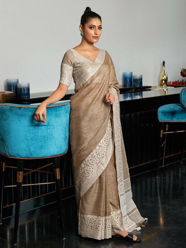An elegant beige woven linen saree with a contrast zari border and tassel detailing.